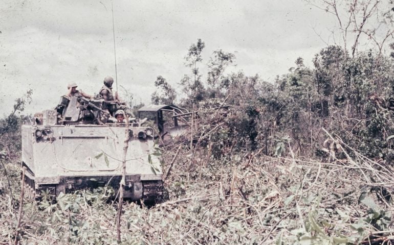 A military vehicle driving through a forest filled with trees