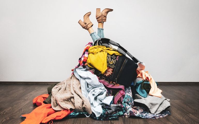 woman legs out of a pile of clothes on the floor. shopping addiction concept