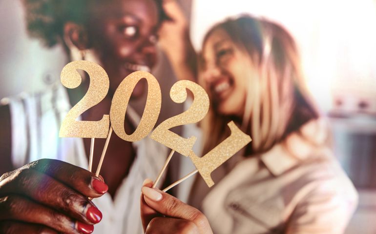 Woman celebrating 2021 in New Year’s Eve holding party numbers