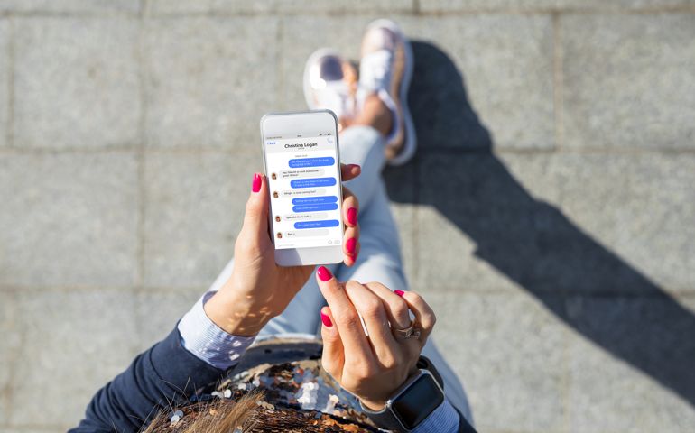 Woman using instant messaging app on mobile phone, view from above