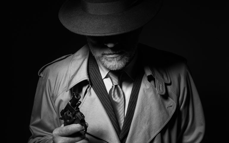 Undercover agent holding a pistol in the dark, 1950s noir film character