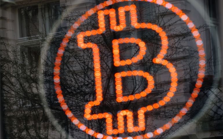 A bitcoin LED sign diplayed in a shop window offers service.
