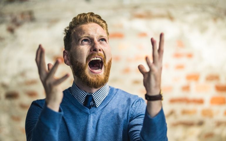Young redhead businessman shouting from frustration.
