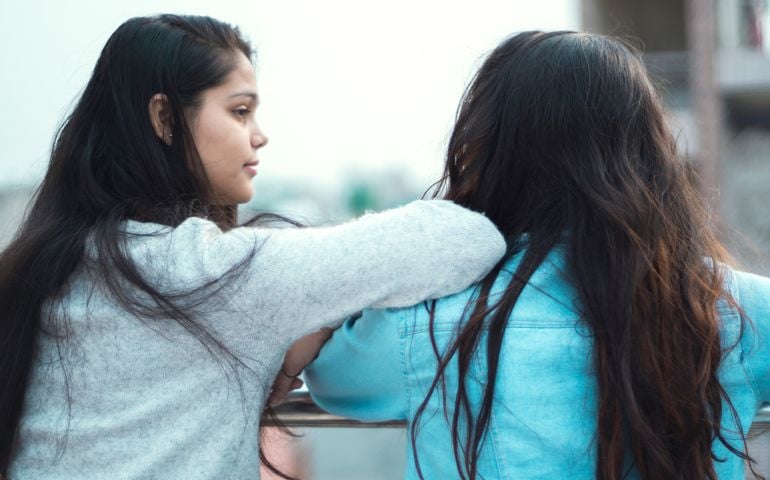 Indian young woman consoling to a depressed friend. outdoor shoot, girls standing in balcony. copy space