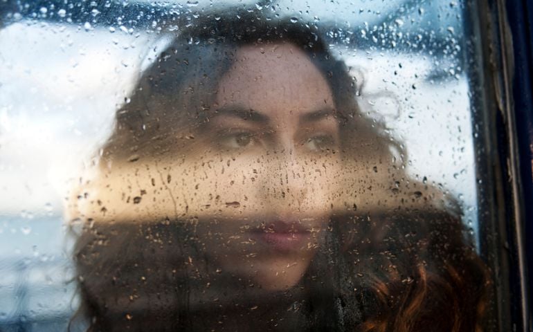 portrait of female through rain covered window