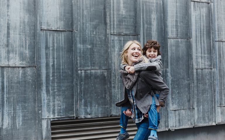 Happy mother carrying son piggyback