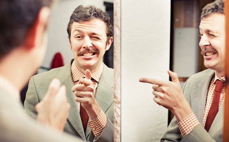 Man pointing at reflection in mirror