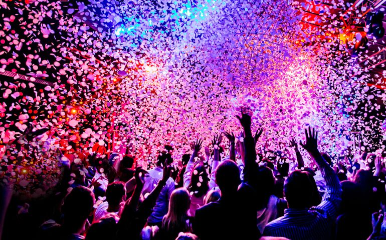 silhouettes of concert crowd in front of bright stage lights and confetti