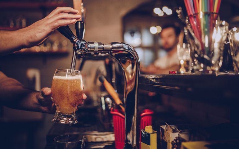 Man in pub pouring beer.