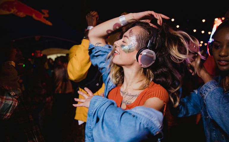 Young woman is dancing with her friends in a silent disco.