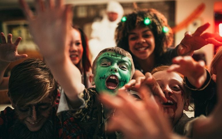 Group of young friends dressed in costumes reaching out towards the camera like zombies.