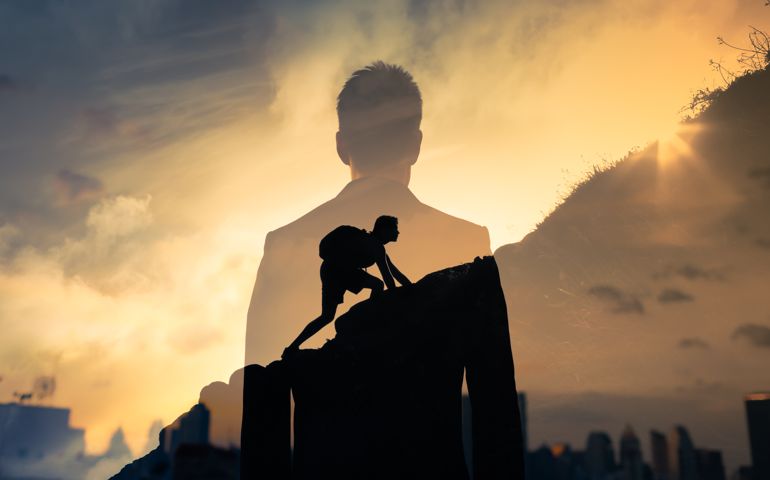Man feeling determined climbing up a steep mountain side.