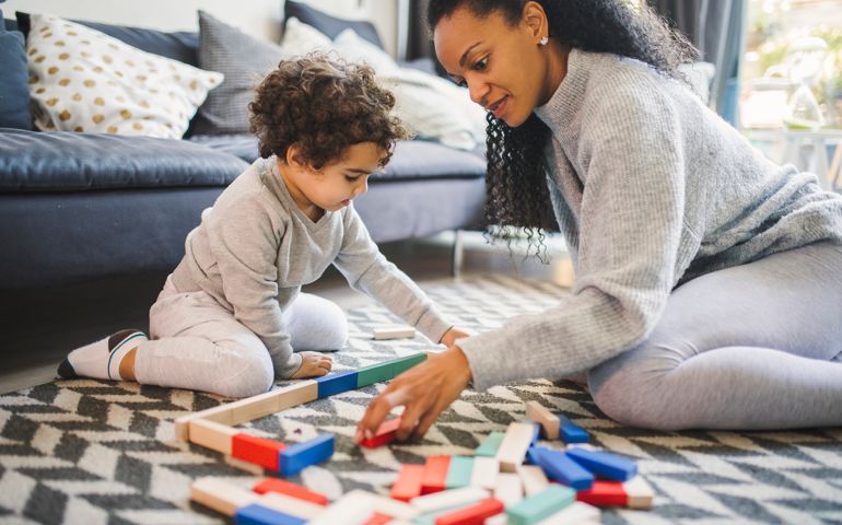 Cute boy play board game with his mother