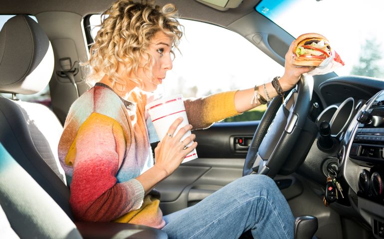 Eating burgers from a fast food chain while driving a car.