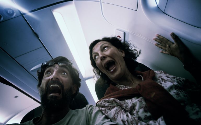Two passengers scream in fear in what could be a plane accident, or them just being over conscious. Motion blur and shallow depth of field with focus on man's eyes.
