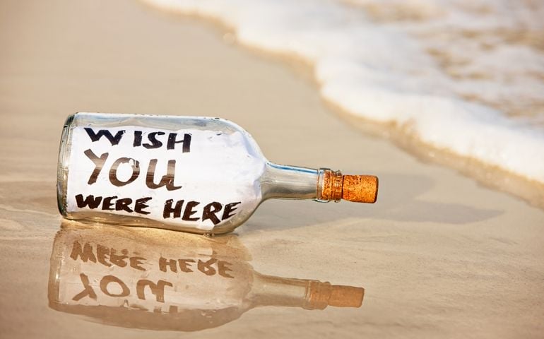 On wet sand at the water's edge lies a message in a bottle from a castaway seeking company: Wish you were here!