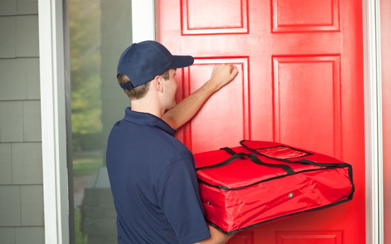A take-out pizza delivery man delivering take-out food to