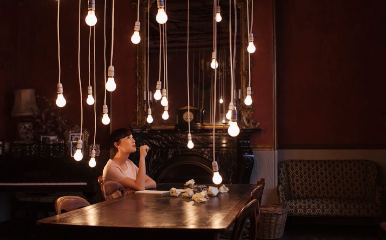 Woman sitting at table with hanging lightbulbs