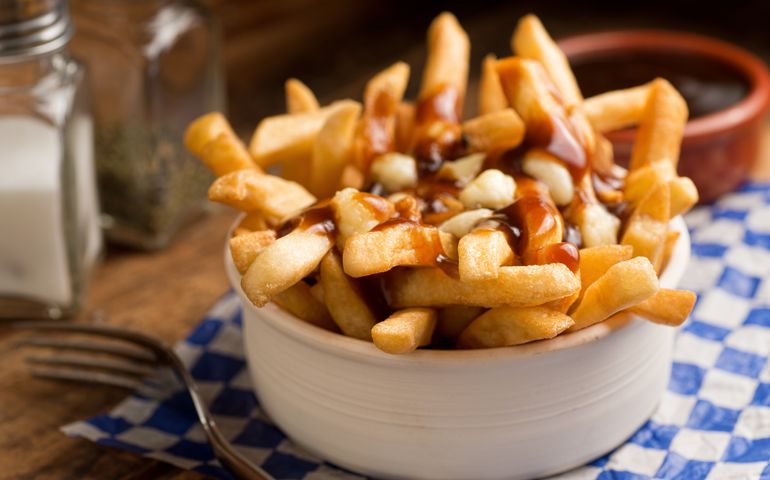Classic French Canadian poutine with french fries, gravy, and cheese curds on a rustic tabletop.