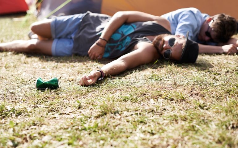Shot of two young men lying on the grass after drinking too much at an outdoor festival