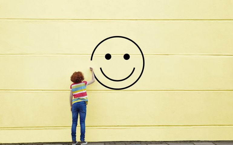 Girl drawing smiley face on to a wall