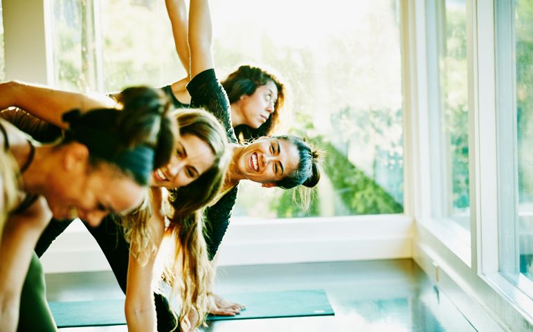 Smiling woman laughing with friends during yoga class in studio