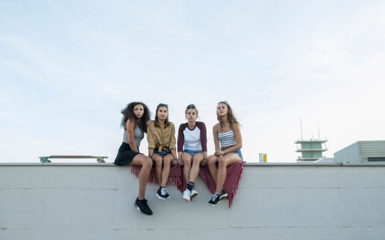 Teenage girls sitting on rooftop wall
