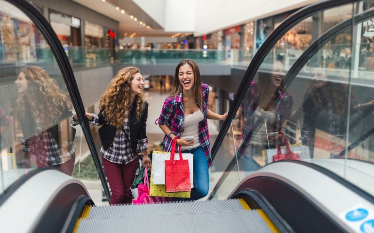 Young women in the shopping mall using the escalator to move on the upper floor