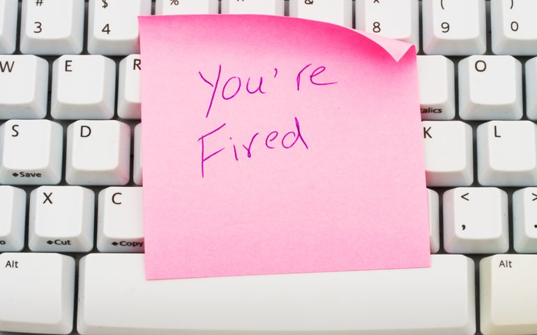 A pink sticky note sitting on a computer keyboard, You are fired