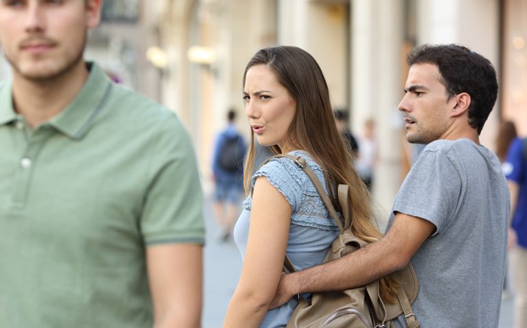 Disloyal woman looking another man and her angry boyfriend looking at her on the street