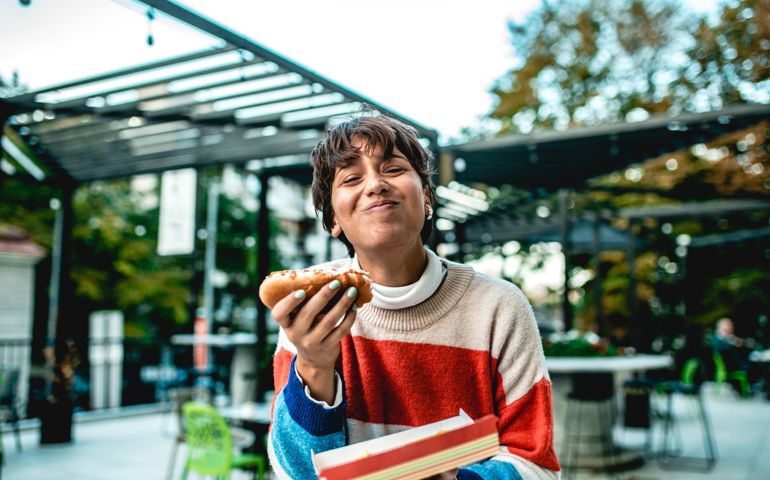 a young girl holds a fast food meal in her hand while she laughs and looks at the camera