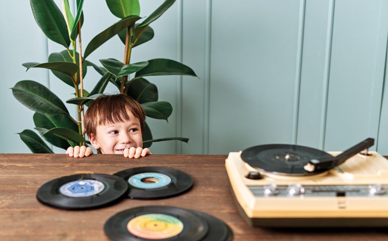 Cute child listening to music on table