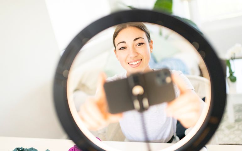 Young Woman Influencer setting up smart phone in ring light for crochet vlog
