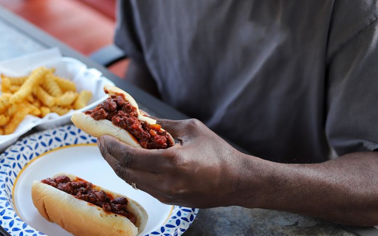 An African-American man eating a chili dog at a picnic