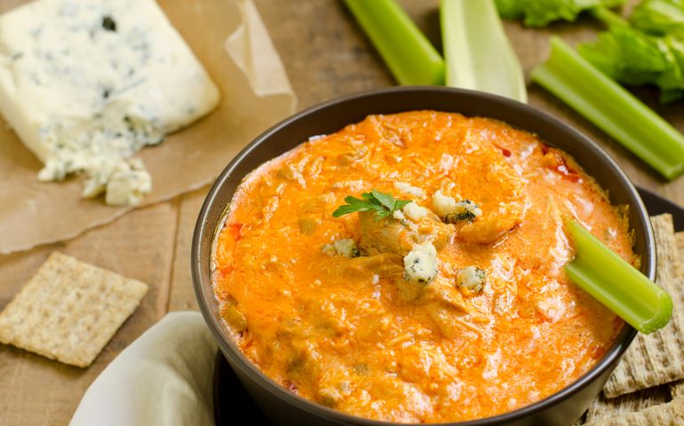 A bowl of Buffalo Chicken Wing Dip with blue cheese and celery in the background and crackers on the side.Similar Images:
