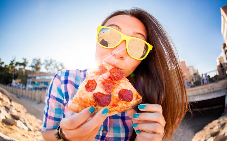 Close-up Of A Happy Young Woman Wearing Sunglasses Eating Pizza