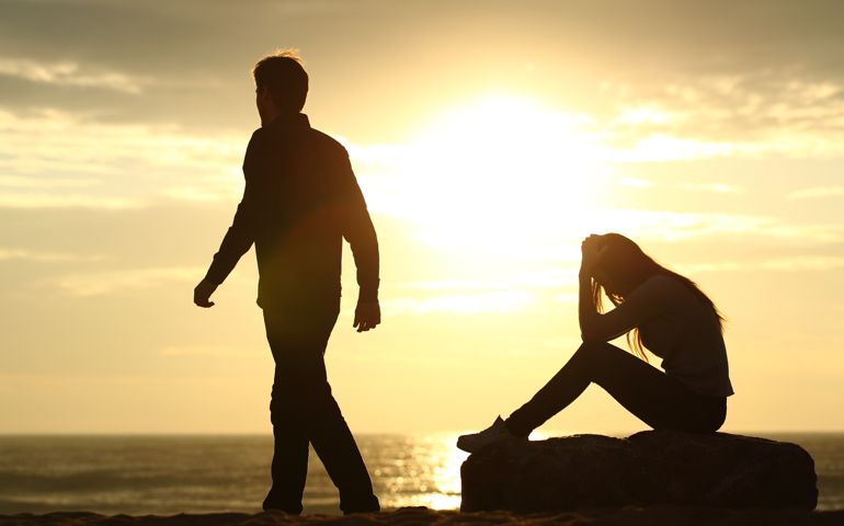 Couple silhouette breaking up a relation on the beach at sunset