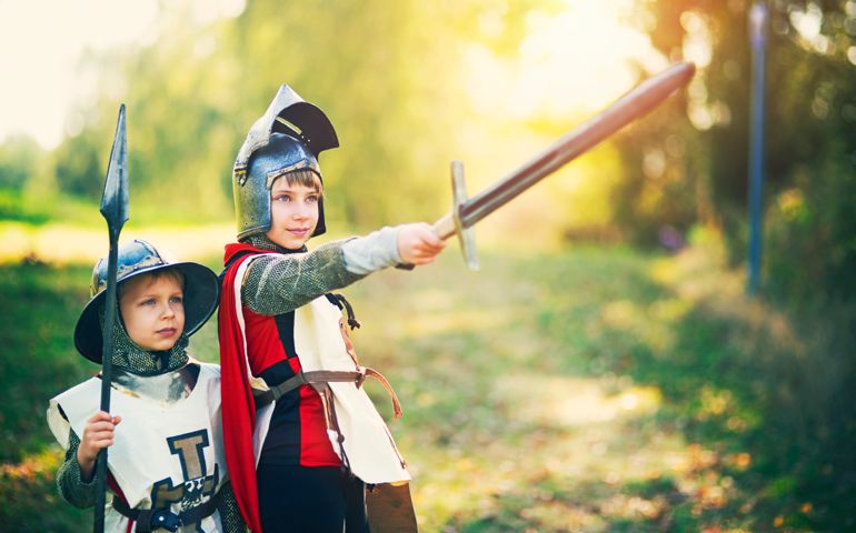Kids dressed up as knight and squire playing in forest. Little boy is aged 6 and the girl is aged 9.