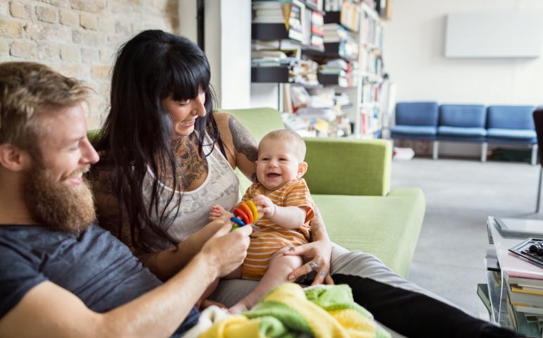 Young couple at home relaxing with their new born child on couch