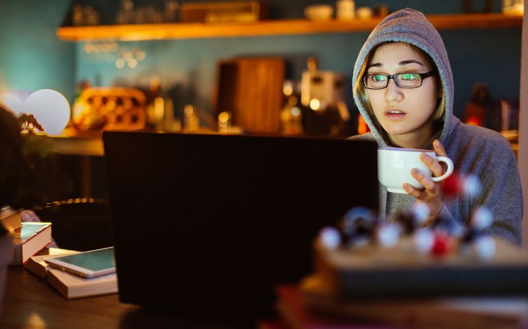 Young woman watching a movie, using laptop at home.