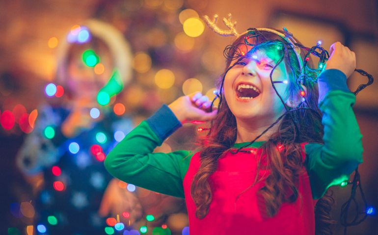 Little girl and boy in Christmas playing with lights