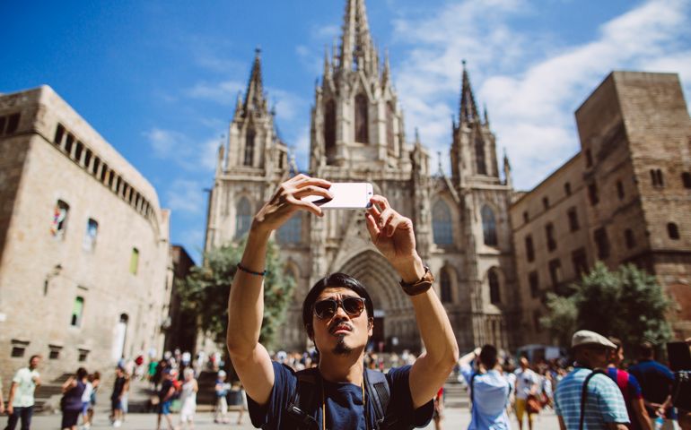 Young asian man taking a selfie in front of the Barcelona Cathedral in Spain.