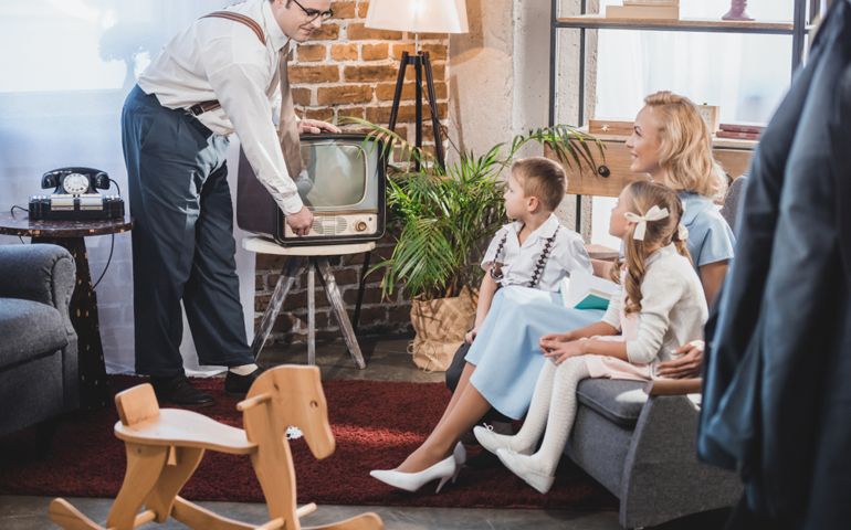 happy mother with two children looking at father turning on vintage tv, 50s style