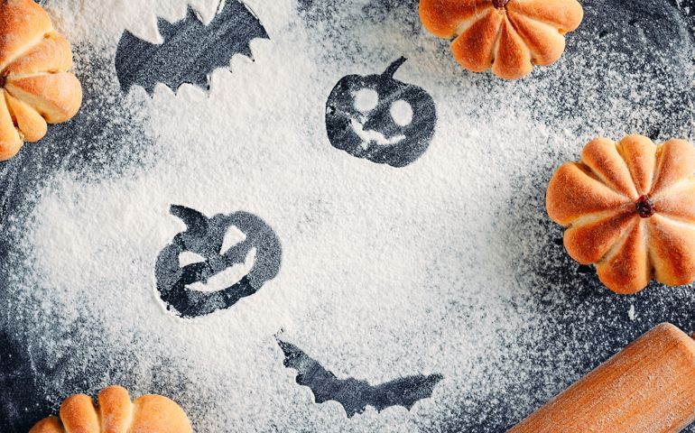 Drawing Halloween decorations on flour background, cakes in shape of pumpkin and rolling pin. Halloween cooking concept