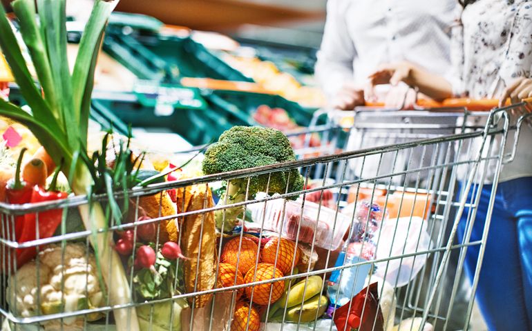 Unrecognizable young couple with a full shopping cart of groceries at a convenience store.