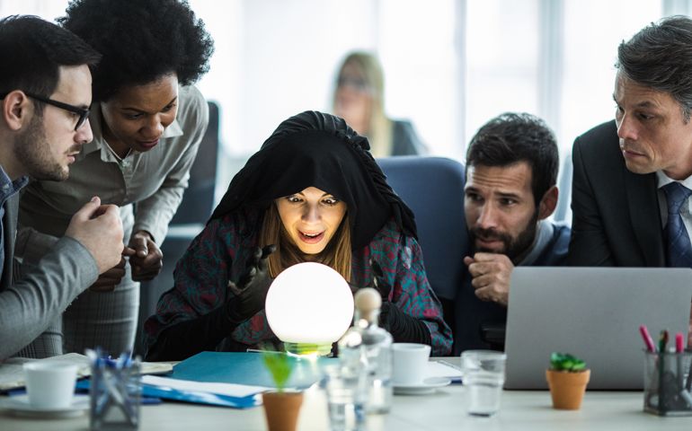 Female fortune teller analyzing crystal ball while predicting the future of business people.