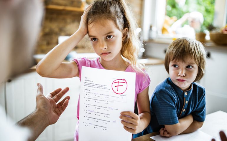 Little girl feeling sad while showing her parent a negative test results at home.