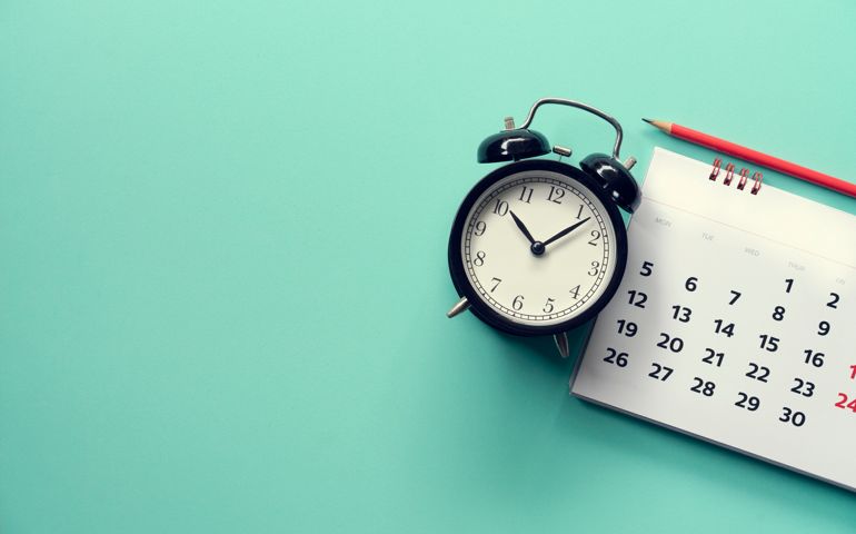close up of calendar and alarm clock on the green background, planning for business meeting or travel planning concept