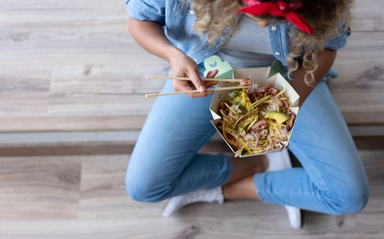Close-up on a woman eating a poke bowl at home while moving house