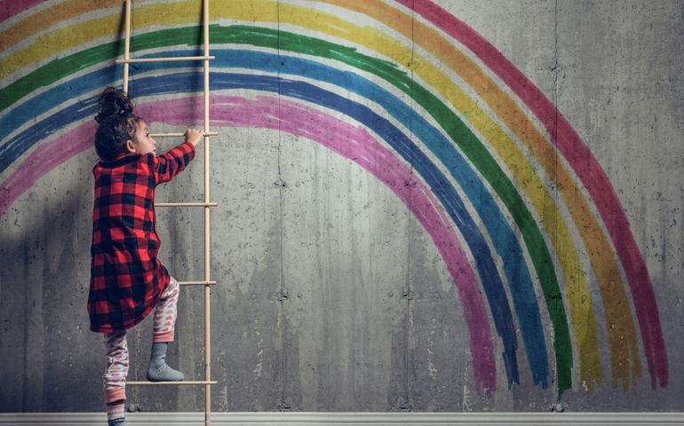 Girl climbing to reach the rainbow